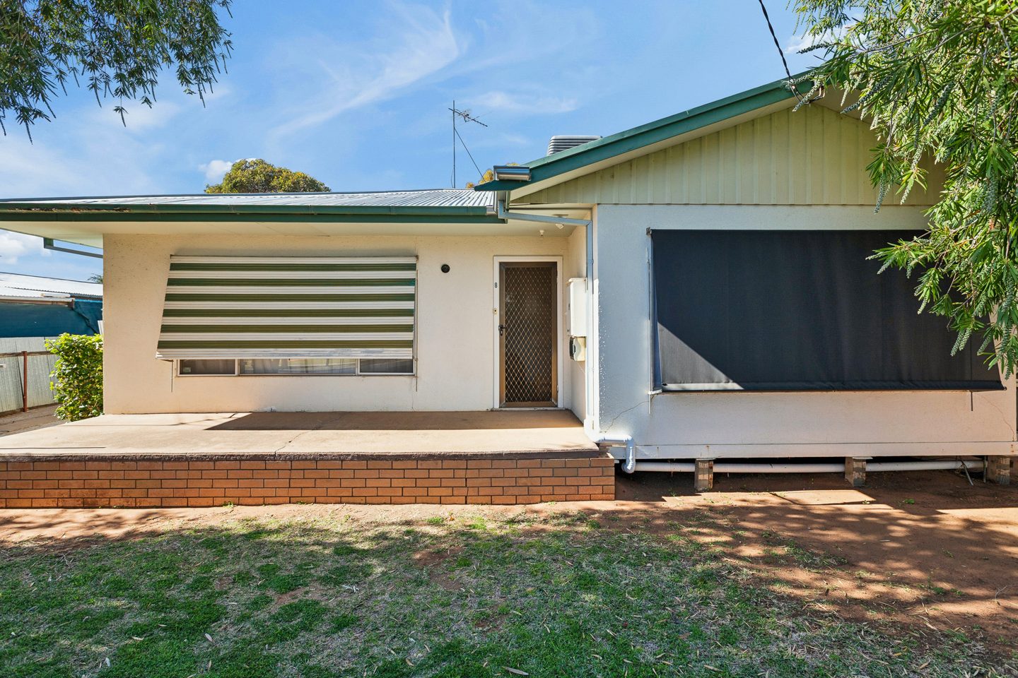 The conite frontage with green-striped awning, porch and green roof trim