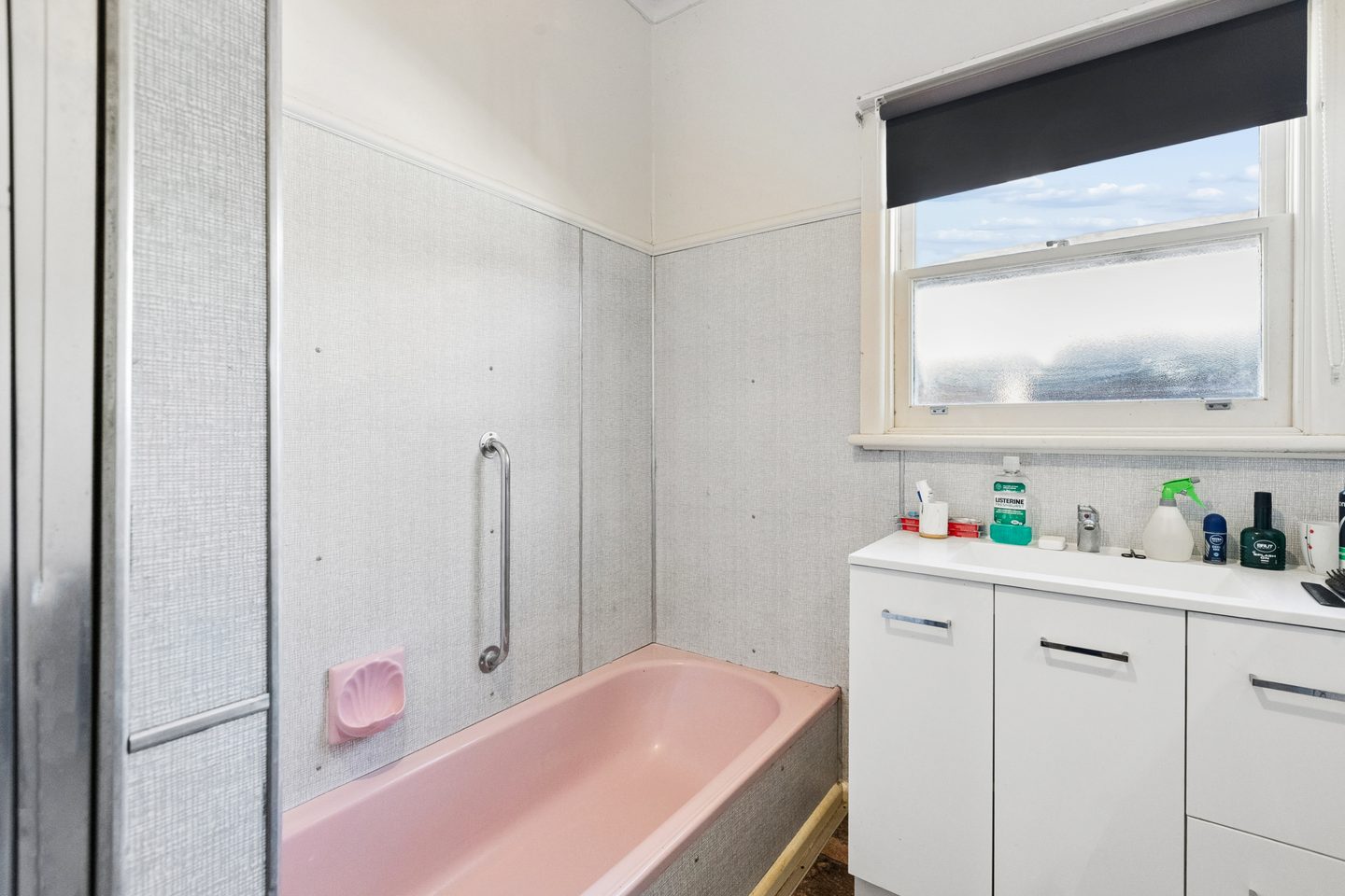 Bathroom with pink bath, separate shower and white vanity