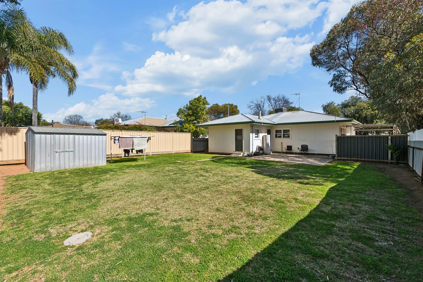 Lawned backyard with garden shed and paved patio beside the home